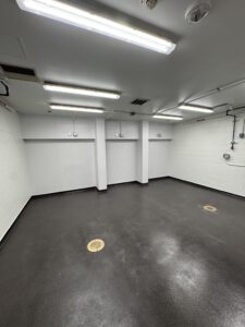 Image of an empty room with new floors and paint and plumbing for future fish tanks.