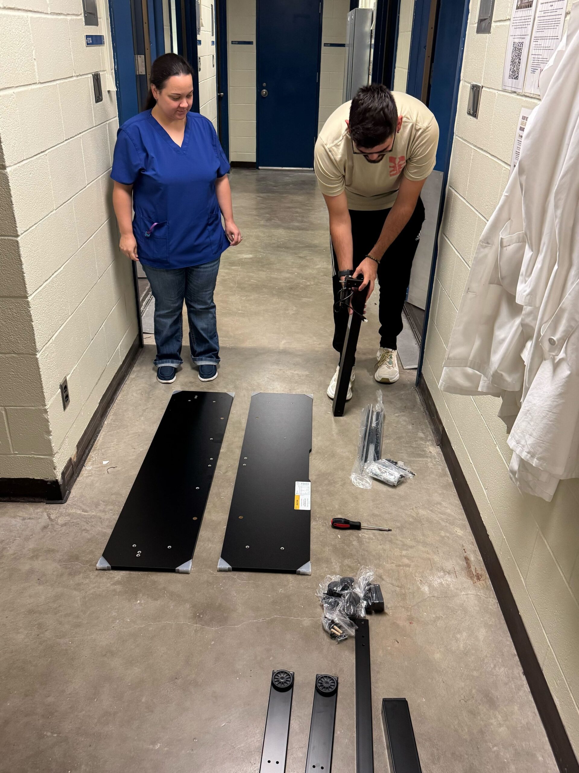 Our new employee Islyn watches as Jacob plans the next step in the assembly of a standing desk.